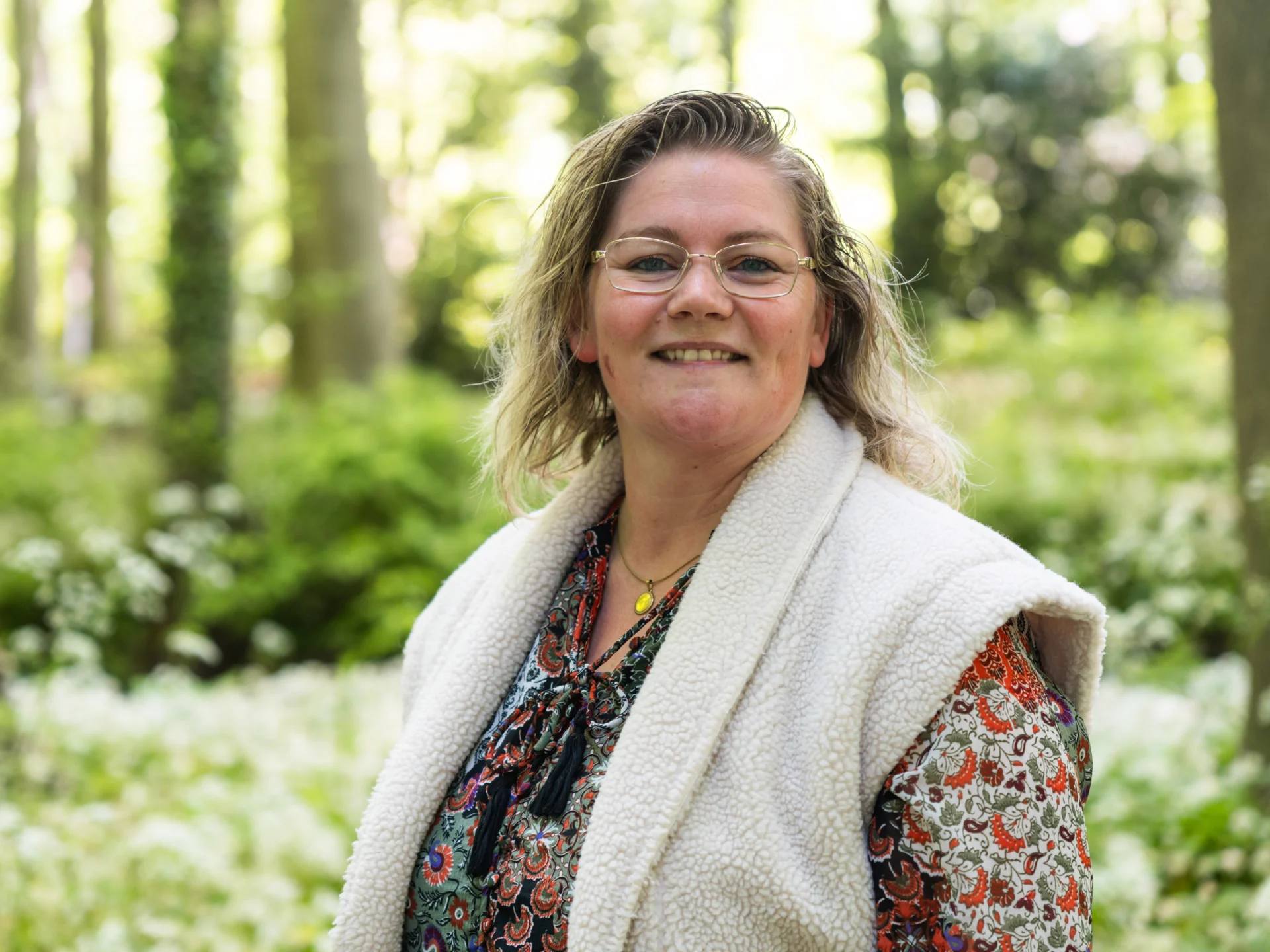 Danielle staat in de natuur met een witte bodywarmer van stof