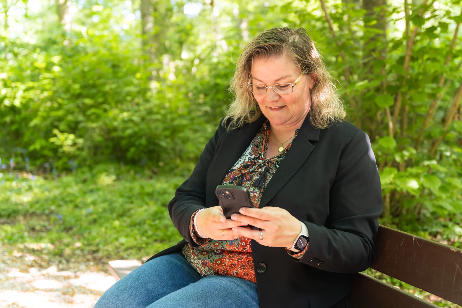 Danielle zit op een bankje en kijkt naar haar mobiel